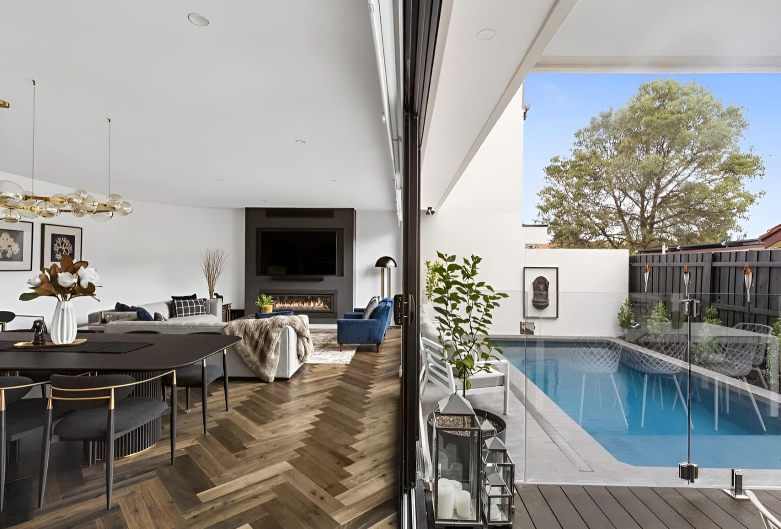 Open-plan living and dining area flowing to outdoor pool through large sliding glass doors